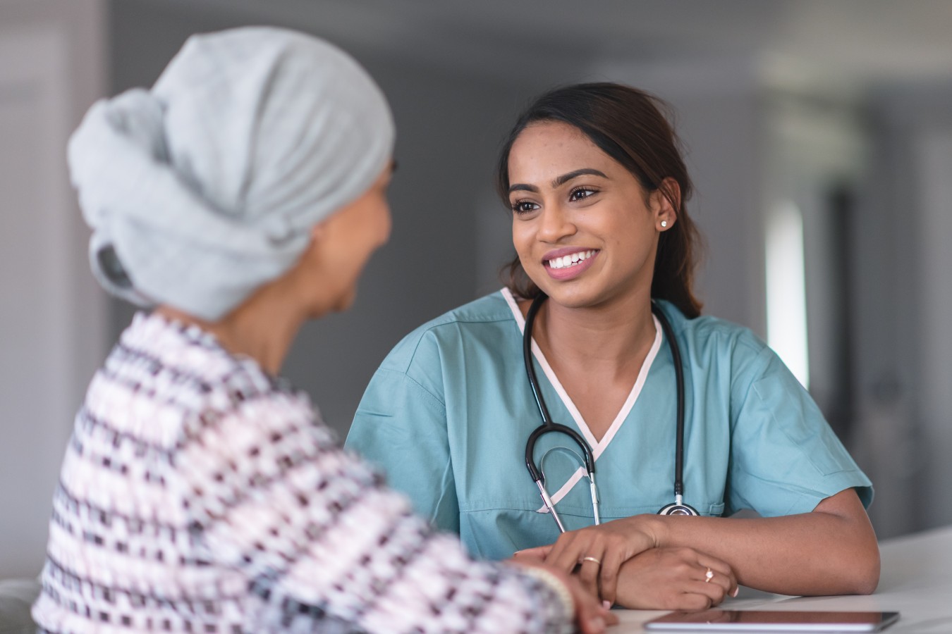 Photo showing a doctor talking to a patient in an oncology center. The doctor explains the eligibility criteria for the Sonobird clinical trial to treat her glioblastoma.